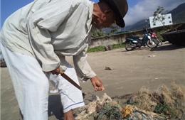Lão ngư nhặt lưới cước nơi cửa biển