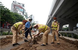Hà Nội: Cảnh sát giao thông thu gom đất rơi vãi tại lối lên đường vành đai 3, đảm bảo an toàn cho người dân đi qua